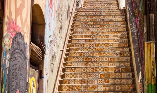 Tiled staircase in Valparaiso, Chile with street art on the walls either side