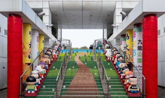 A staircase painted to look like a winding path through a field, with 3D cartoon style figures lining each side
